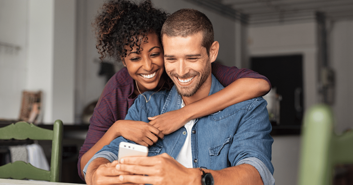 Couple looking at an debt reduction progress on their phone and smiling